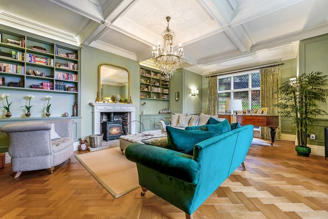 The drawing room has a woodburning stove within feature fireplace, an oak floor and large windows with diamond-patterned panes.