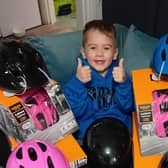 Little Marli Barnes from Sowerby Bridge with some of the helmets he is handing out to other children after his accident