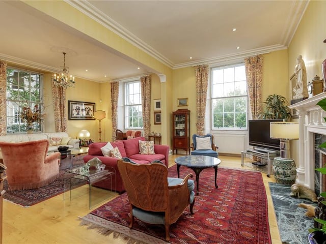 The drawing room has three sash and case windows, a feature fireplace, and detailed cornicing.