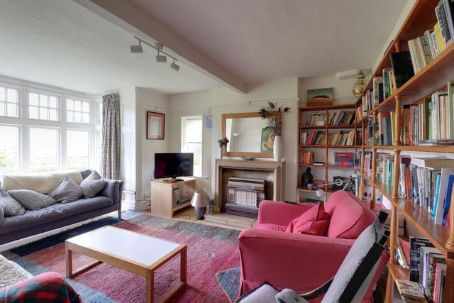 A large and bright reception room with bay window and built-in bookshelves.