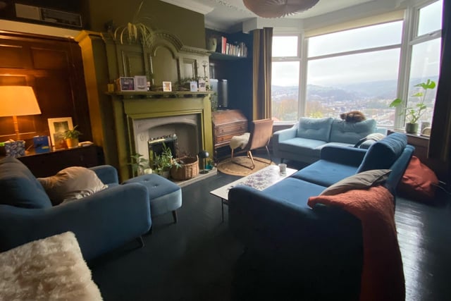 The wood panelled sitting room, with feature fireplace, has a wide bay window looking out over the valley.