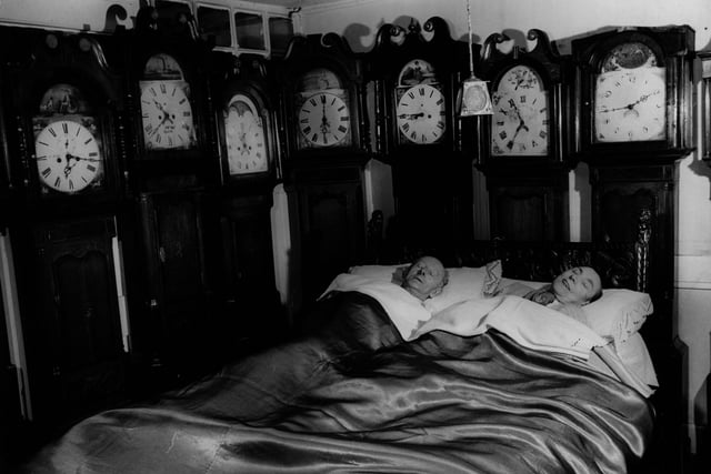 Mr and Mrs Charles Bromley of Belper, Derbyshire, at home with part of their collection of 109 grandfather clocks. in 1955.