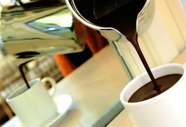 Hot chocolate is poured into a mug