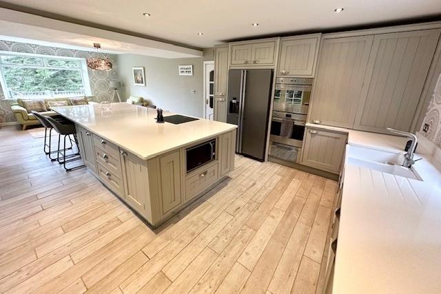 The bespoke kitchen with fitted units and granite worktops has integrated appliances and a large central island.