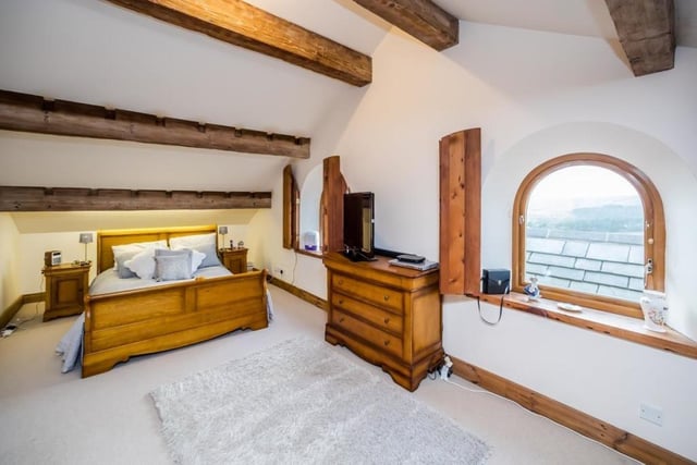 An arched window is a feature in this double bedroom, with ceiling beams and window shutters.