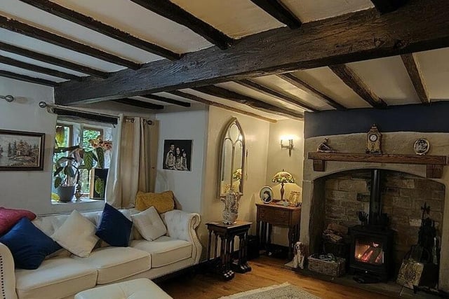 A beamed sitting room with large feature fireplace and woodburning stove.