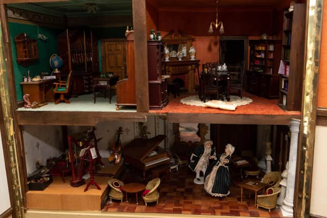The interior features items such as dolls, furniture, small household items, croquery, musical instruments.