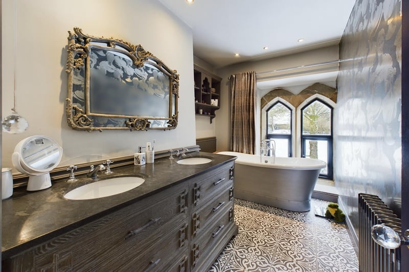 A beautiful bathroom with free standing bath and shower, and his and hers washbasins within a large vanity unit.