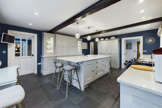 The Drew Forsyth shaker-style breakfast kitchen has a central island, a pantry, and a black five-oven Aga among its facilities.
