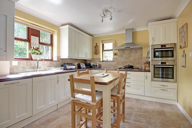 The breakfast kitchen has a limestone tiled floor, shaker-style units and integrated appliances.