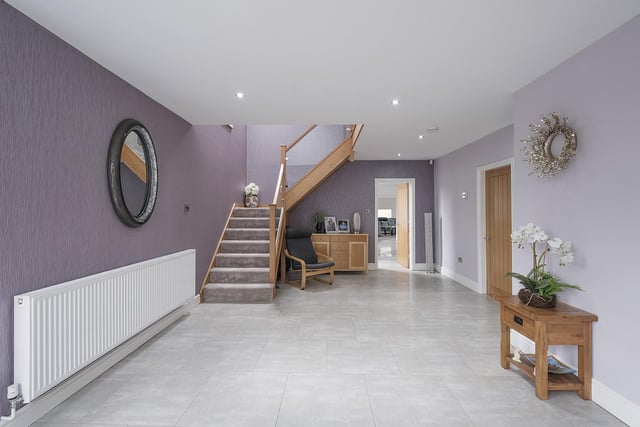 The staircase with oak and glass balustrade leads up to a gallery landing from the hallway.
