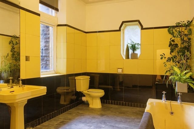 This large bathroom is mostly tiled and has a feature window.
