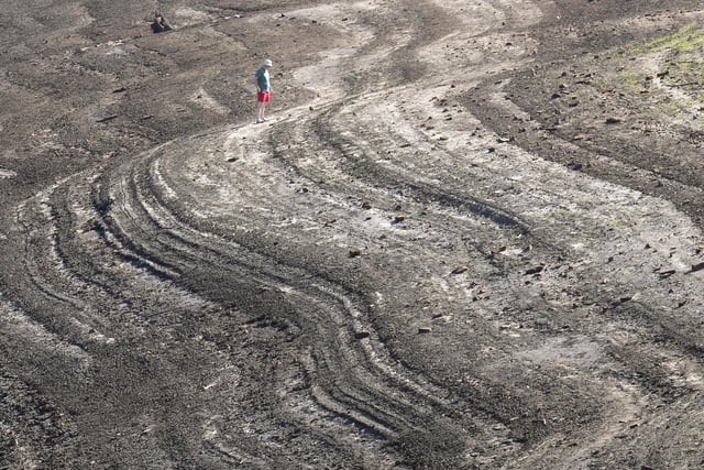 People walk on the dried out bed at Baitings Reservoir. (Photo by Christopher Furlong/Getty Images)