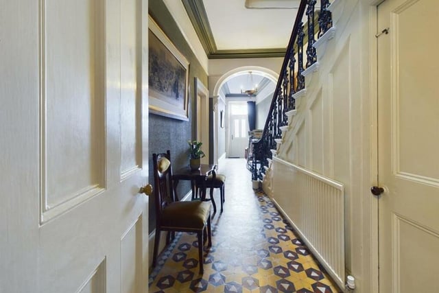 A grand hallway has the staircase with ornate spindle balustrade leading to the two floors above.