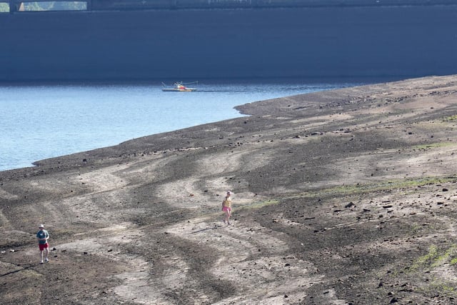 People walk on the dried out bed at Baitings Reservoir. (Photo by Christopher Furlong/Getty Images)
