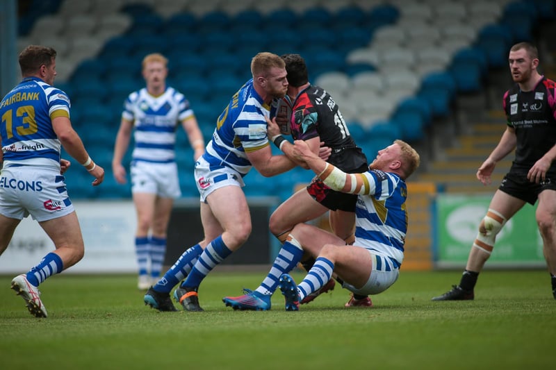 Dan Murray and Will Calcott of Halifax tackle Callum Field of Widnes