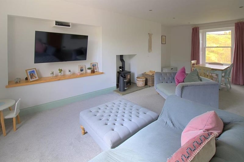 The spacious lounge with dining space, with chimney breast feature housing a multi-fuel stove.
