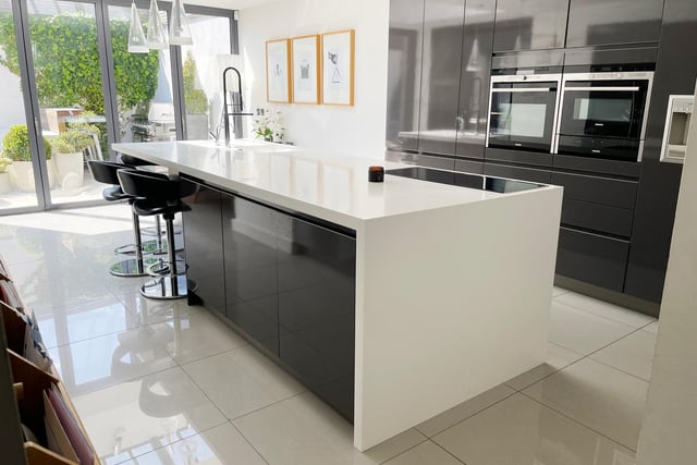 A Corian central island features in the kitchen, with floor to ceiling units and integral appliances that include a Gaggenau fridge freezer and full height wine fridge, a Siemens oven, microwave oven, plate warming drawer, a four-ring induction hob with ceiling inset extraction and Bosch dishwasher. Natural light filters through electric roof light windows