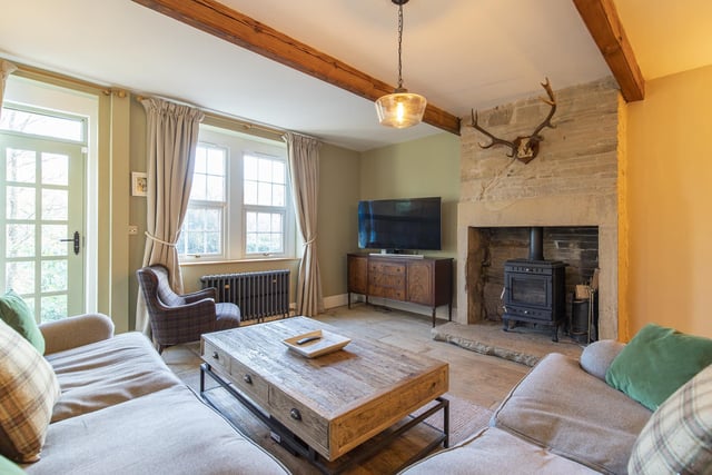 A warming stove within an open stone fireplace is a central feature in this beamed sitting room.