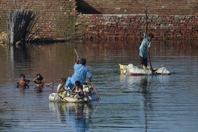 People use rafts to cross a flooded area after monsoon rains on the outskirts of Sukkur, Sindh province, on September 1, 2022 (Photo by ASIF HASSAN/AFP via Getty Images)
