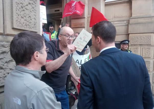 A demonstrator challenges Conservative group leader Coun Scott Benton, right