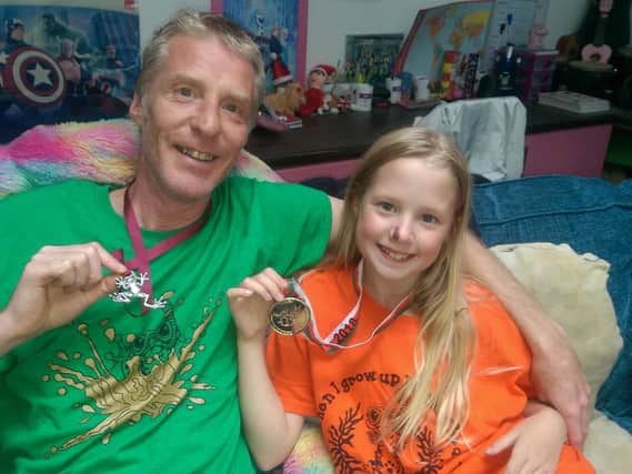 Jason Blackbond and daughter George pose with their medals from the World Bog Snorkelling Championships in Wales.