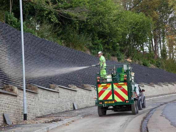 Hydro-seed being sprayed onto the green wall up Salterhebble Hill