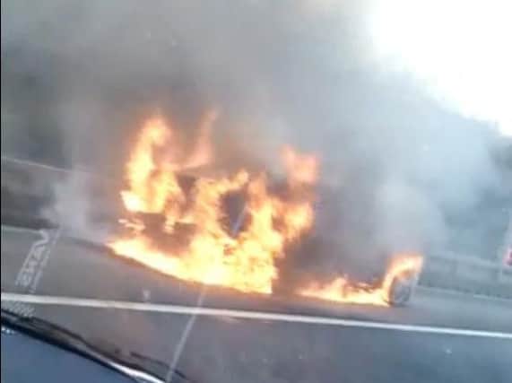 Cars speed past a burning car on the M62 this morning.