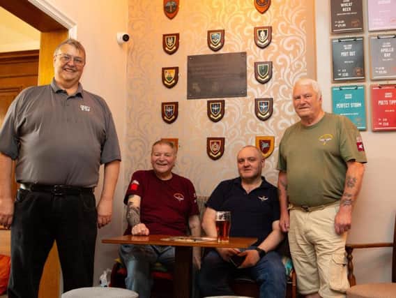 Steve Francis, Jay Jay Johnson, Phil Hull and Paul Boyd, with the wall of war veterans' plaques.