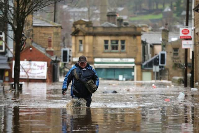 HEBDEN BRIDGE, ENGLAND - DECEMBER 26: A man wades through floodwaters as rivers burst their banks on December 26, 2015 in Hebden Bridge, England. There are more than 200 flood warnings across Britain as home and business owners prepare for serious flooding. The army has been deployed to some villages to bolster flood defences as rain continues to fall across the north.  (Photo by Christopher Furlong/Getty Images)