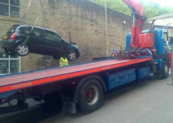 A Renault Clio damaged in a crash in Dean Clough, Halifax, is towed away