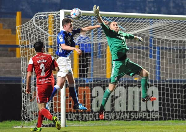 Macclesfield's Paul Lewis challenges from FC Halifax Town goalkeeper Matt Glennon during the midweek game at Moss Rose.