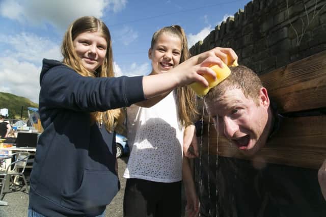 Grandma Pollards Chippy car boot sale and fun day, Walsden. From the left, Ellie Parkinson-Doyle, 13, Molly Kirby, 12, soak Andy Jones in the stocks.