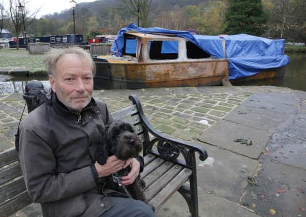 Brian Toberman, with his dog Bella, by his burned out canal boat at Hebden Bridge Marina