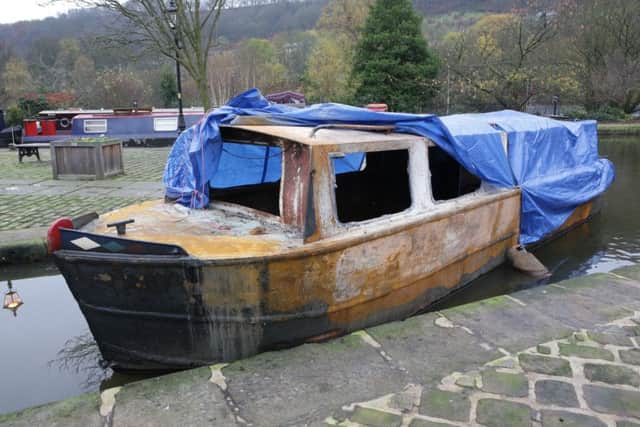 Brian Toberman, with his dog Bella, by his burnt out canal boat at Hebden Bridge Marina.