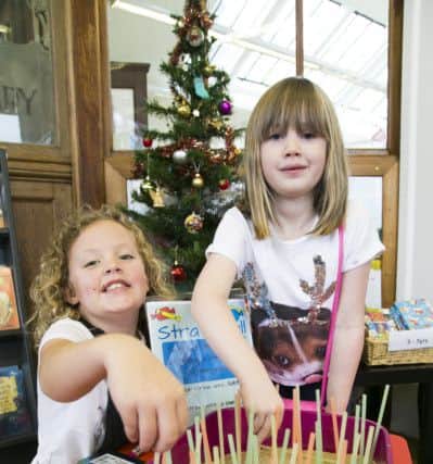 Christmas Fair at Rastrick Library. Mya Rhodes, eight, left, and Harriet Lester, six, pulling straws.