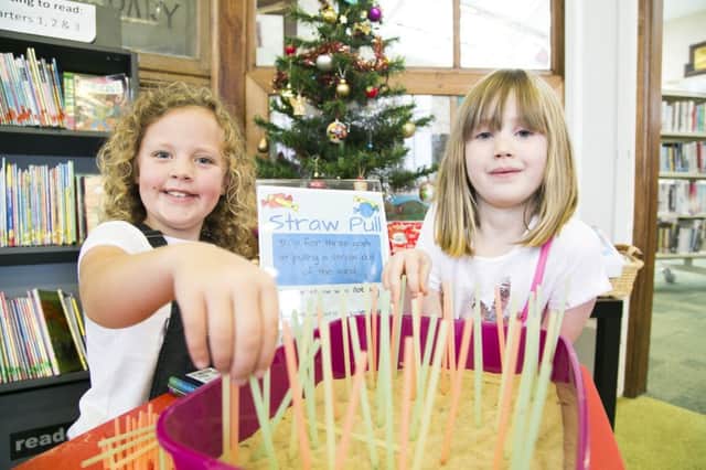 Christmas Fair at Rastrick Library. Mya Rhodes, eight, left, and Harriet Lester, six, pulling straws.
