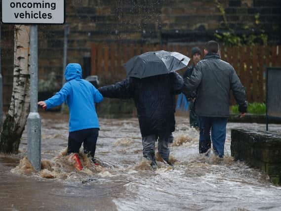 People wade through flood waters at Mytholmroyd in Calderdale, West Yorkshire, where flood sirens were sounded after torrential downpours.