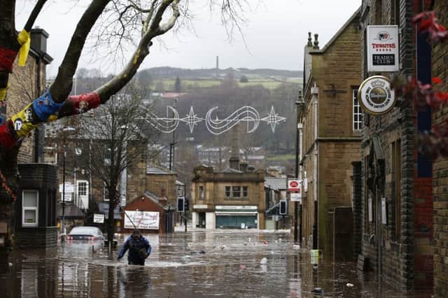 A man wades through flood waters at Hebden Bridge in West Yorkshire, where flood sirens were sounded after torrential downpours.