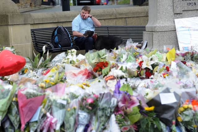 A man wipes away a tear at the flowers for Jo Cox MP.