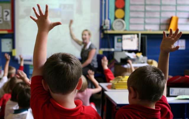 File photo dated 06/07/11 of children at school raising their hands to answer a question as schools admissions policies are being looked into amid worries that summer-born children are falling behind in the classroom.