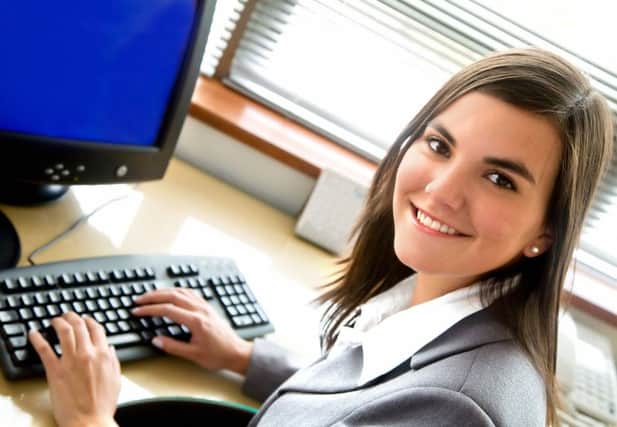 Business woman smiling in an office in front of her desktop computer
