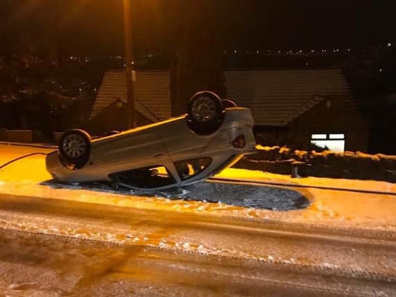 An upturned car in snowy Calderdale.